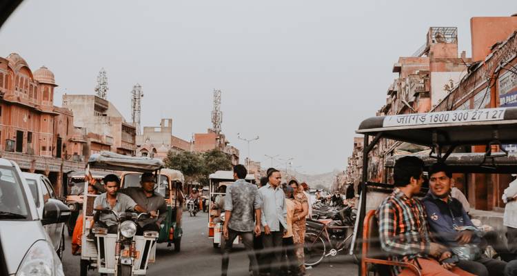 Scène de rue animée avec des auto-rickshaws et des gens.