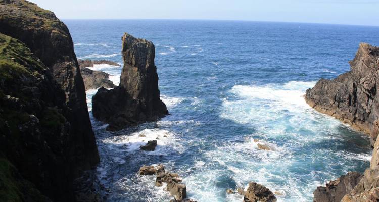 Acantilados dramáticos del mar con formaciones rocosas dentadas golpeadas por las agitadas olas del Atlántico.
