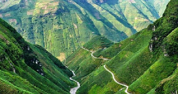 Vallée verdoyante avec route sinueuse et rivière.