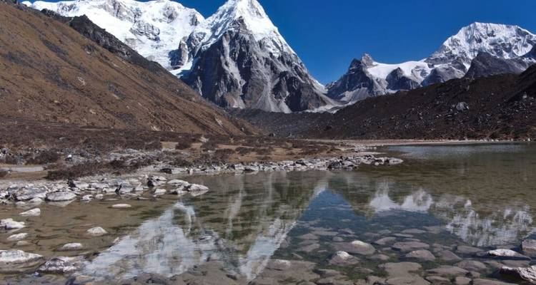 Reflektierender Teich mit klarem Wasser, umgeben von majestätischen schneebedeckten Bergen.