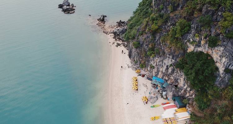 Luchtfoto van een afgelegen strand met kajaks en helder water.