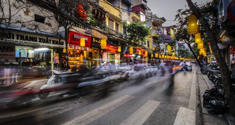 Wazige nachtscène van een drukke straat met winkels en verkeer.