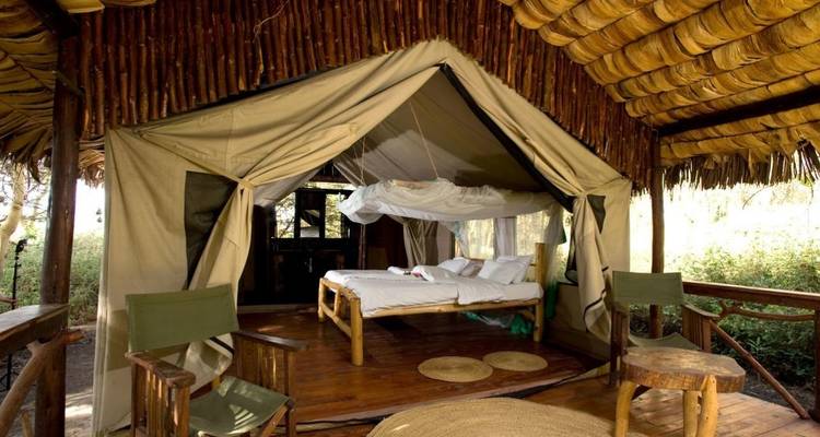 Ein Safarizelt mit Sitzbereich und Moskitonetz über dem Bett.