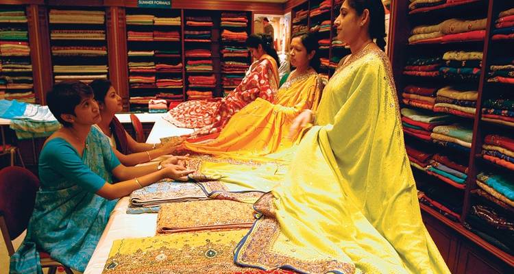 Vrouwen die verschillende kleurrijke stoffen tonen en bespreken in een winkel.