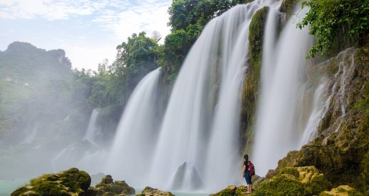 Persona de pie cerca de la majestuosa Cascada Ban Gioc.