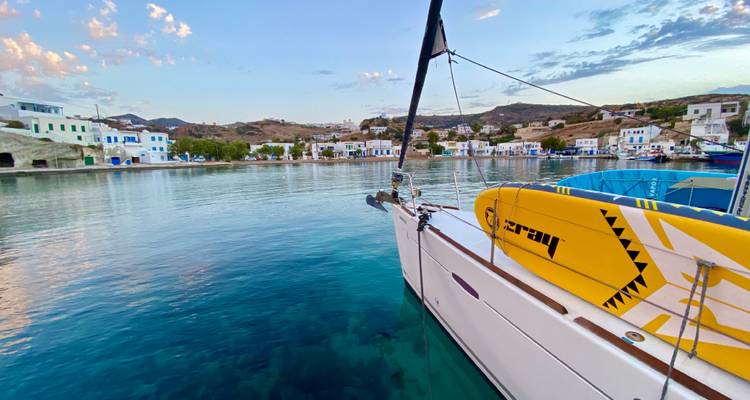 Aangemeerde zeilboot in een heldere blauwe haven met nabijgelegen gebouwen.