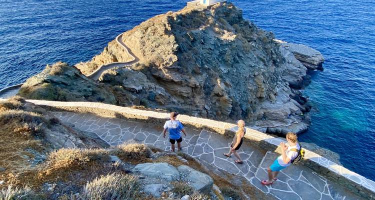 Mensen die wandelen op een pad langs een klif met uitzicht op zee.