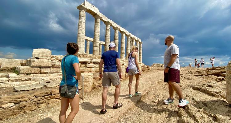 Groep toeristen bij oude ruïnes met zuilen.