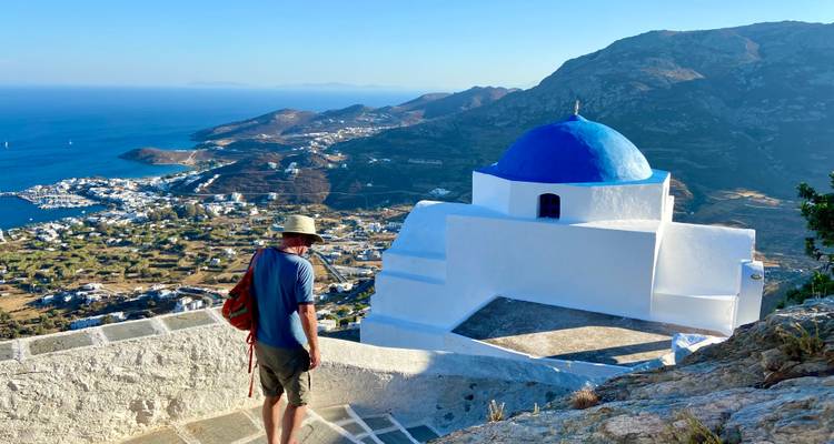 Een persoon die uitkijkt over een kerk met een blauwe koepel met uitzicht op de kustlijn.