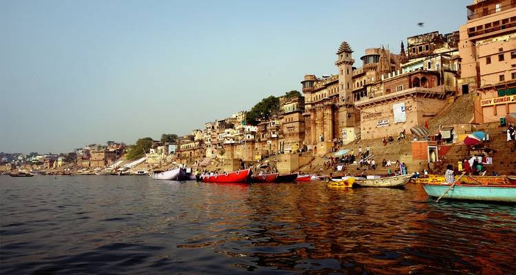 Boats lining the riverbank at the Ganges with activity on the ghats in Varanasi.