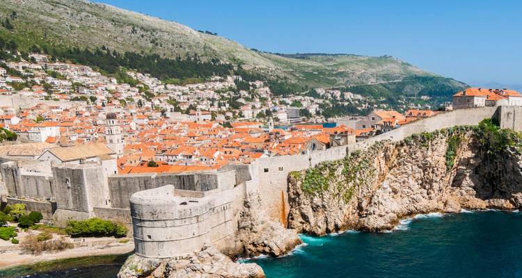 Vue aérienne emblématique des remparts en pierre médiévale de Dubrovnik et de ses toits orange perchés au-dessus de la mer Adriatique aux couleurs vives.