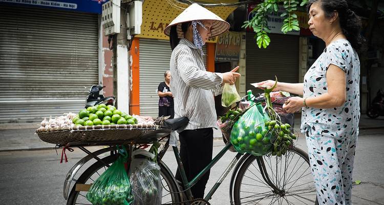 Vendeur ambulant vendant des produits à un client à partir d'un vélo.