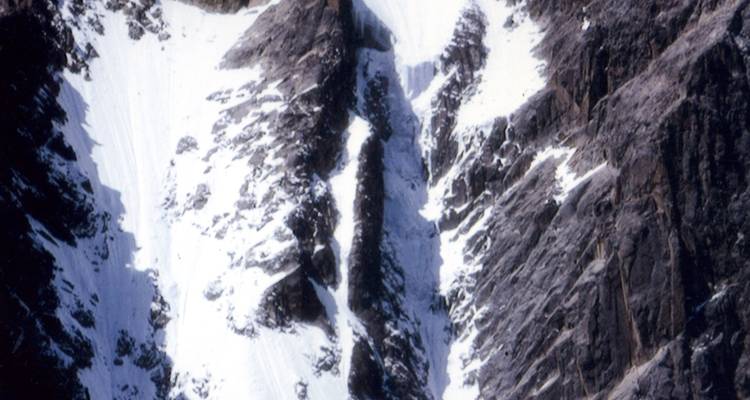 Detailopname van besneeuwde, rotsachtige bergwand.