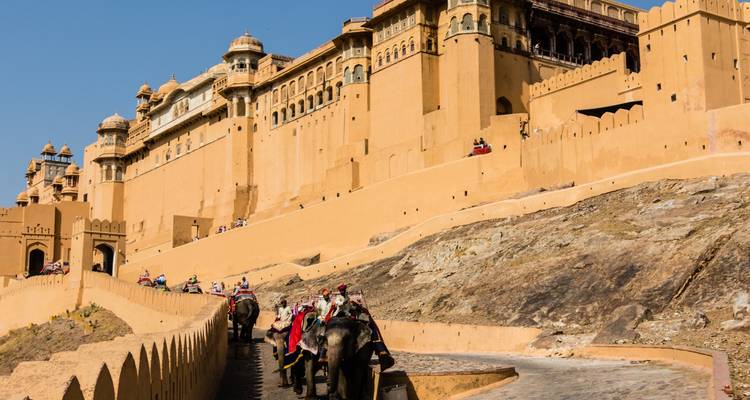 Éléphants avec cavaliers et un fort en arrière-plan.