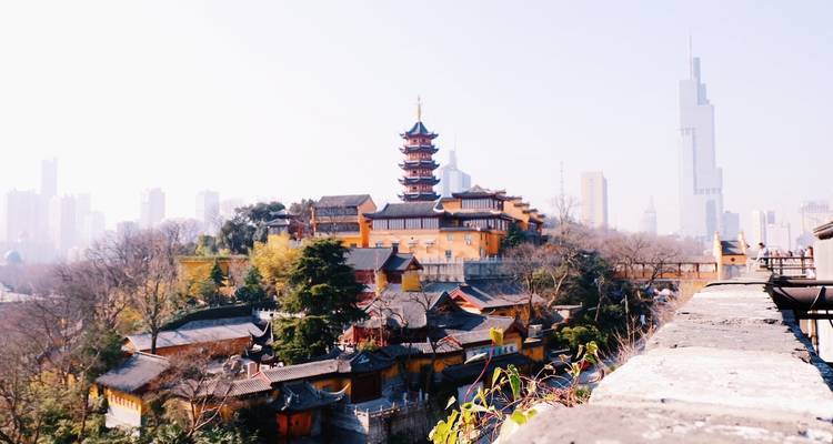 Vue d'un complexe de pagodes anciennes à Nanjing avec les gratte-ciel de la ville moderne flous en arrière-plan.
