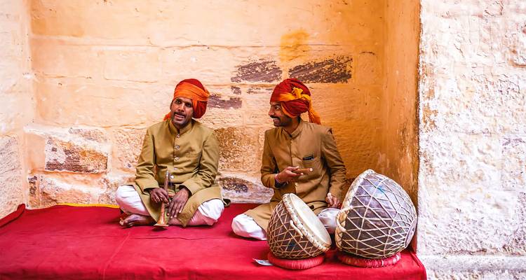 Two musicians in traditional attire sitting with instruments.