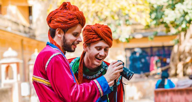 Two men in traditional attire, one holding a camera.