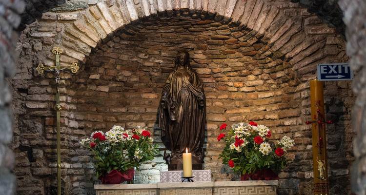 Inneres einer religiösen Stätte mit Statuen und Blumen.