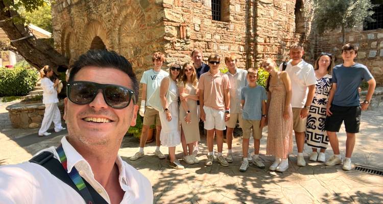 Group of people posing in front of a historic stone building.