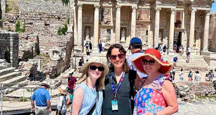 Three women posing with historical ruins in the background.