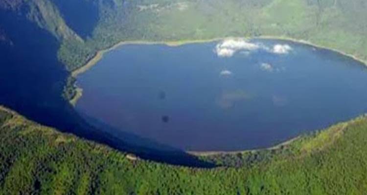 Aerial view of a crater lake surrounded by forest.