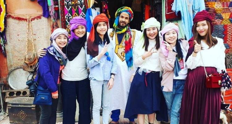 Gruppe von Leuten, die mit einem örtlichen Verkäufer in einem bunten Marktplatz posiert