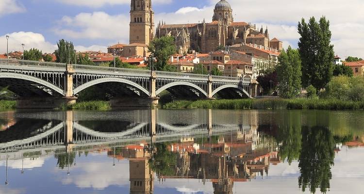 Un paysage urbain historique avec un pont sur des eaux calmes.