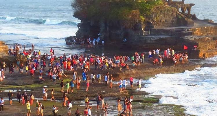 Crowd of people visiting a coastal temple area.