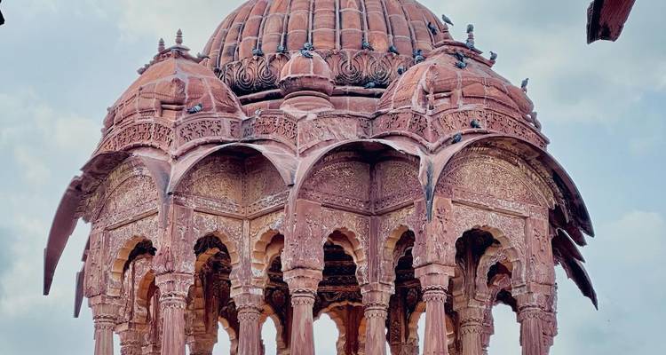 Intricate stone pavilion surrounded by pigeons.