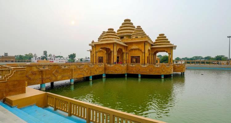 An ornate temple structure over a pond at sunset.
