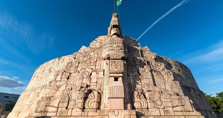 Monumento a la Patria de piedra con relieves mayas detallados bajo un cielo azul profundo