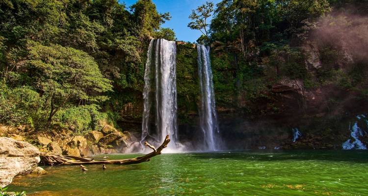 Cascada de selva de dos niveles cae en cascada hacia una piscina esmeralda rodeada de exuberante vegetación