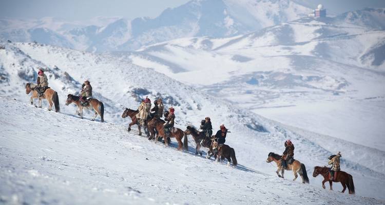 Cavaliers remontant une colline enneigée.