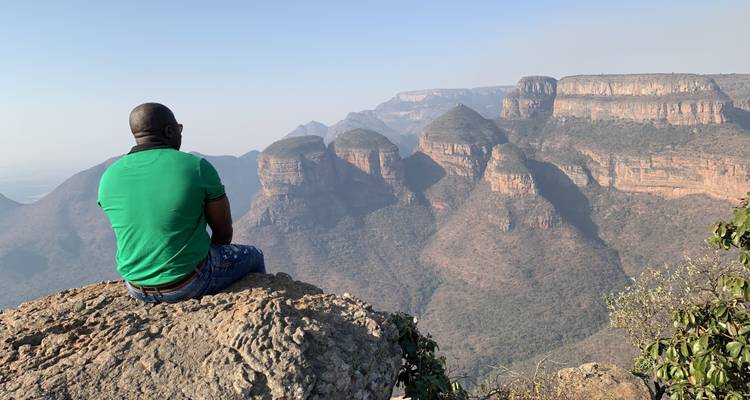 Personne assise sur un rocher surplombant un vaste canyon.