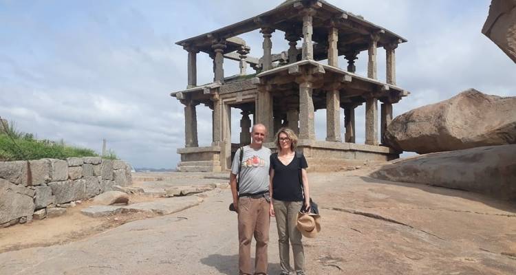 A man and woman posing near an ancient stone structure.