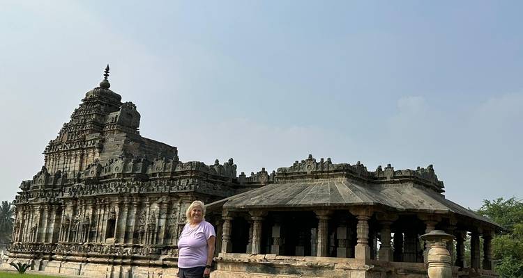 A woman posing in front of a stone temple.