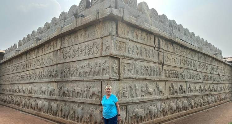 Woman posing in front of an ancient stone structure with carvings.