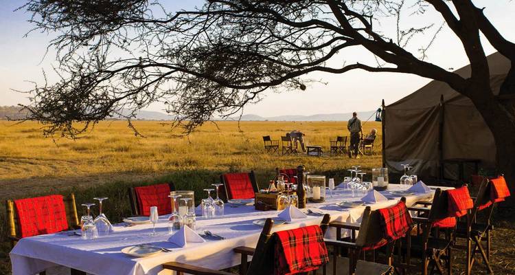 Een gedekte tafel in een luxueuze buitenomgeving met uitzicht op vlaktes.