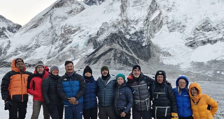 Grupo de excursionistas posando frente a una montaña cubierta de nieve.