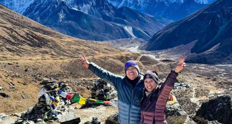 Dos excursionistas felices con los brazos levantados en un paisaje montañoso.