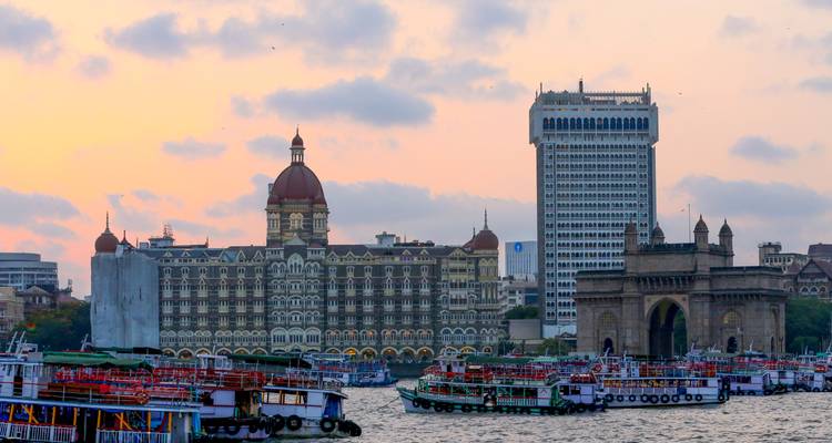 Boats in front of the Taj Mahal Palace and Gateway of India at sunset.