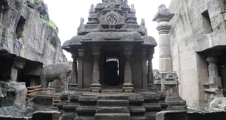 Rock-cut temple with pillar and elephant statue.