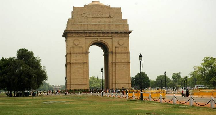 India Gate auf einem weiten Platz mit Touristen, die umherwandeln.