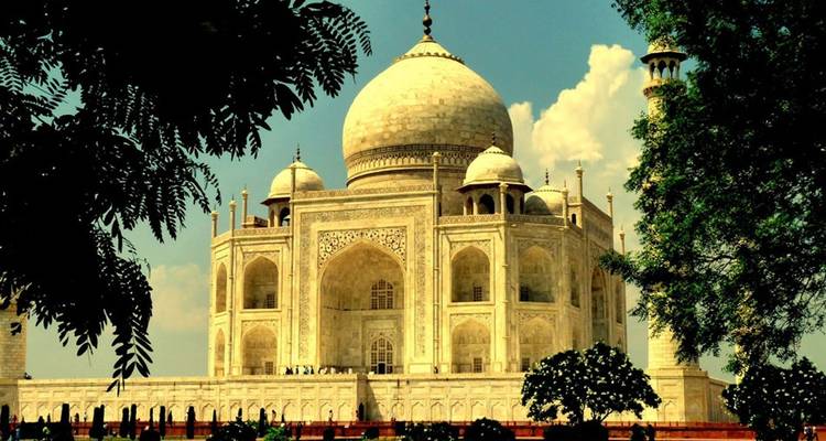 Das Taj Mahal, teilweise von Bäumen verdeckt, mit einem Abendhimmel.