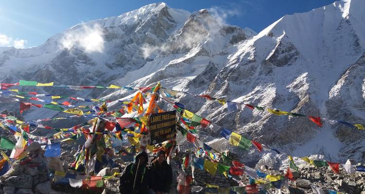 Mensen die staan met gebedsvlaggen tegen besneeuwde bergen.