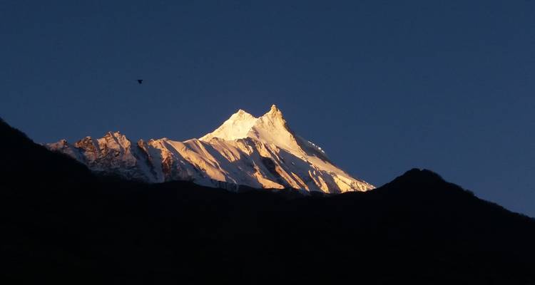 Een met sneeuw bedekte bergtop onder een heldere blauwe hemel.