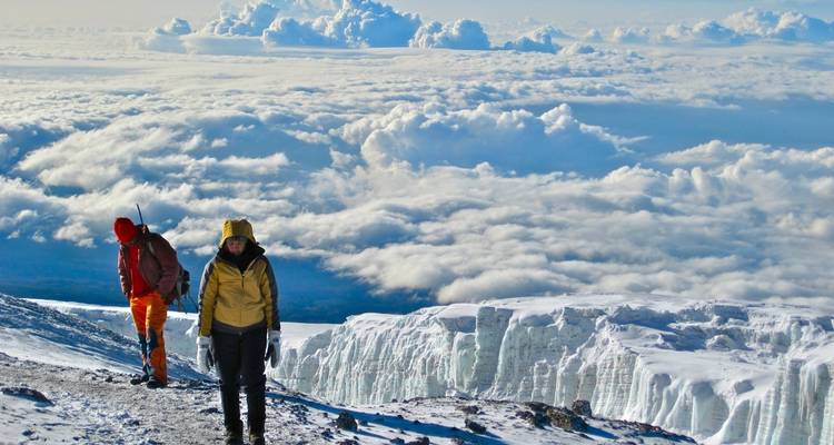 Twee mensen op een besneeuwde pad met wolken en ijsformaties.