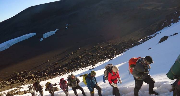 Groep wandelaars die een besneeuwde berghelling beklimmen.