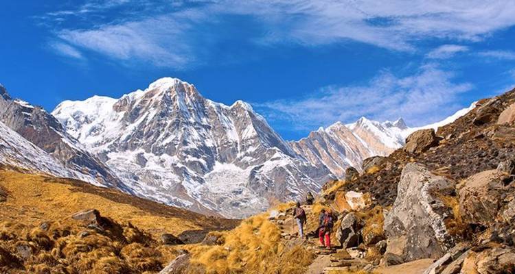 Hikers trekking along a path with snowy peaks