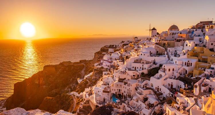 Sunset over the white buildings on cliffs of Santorini.